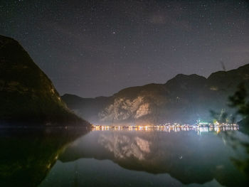 Scenic view of lake by mountains against sky at night