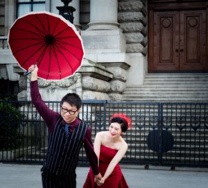 Portrait of happy young woman with red umbrella in city