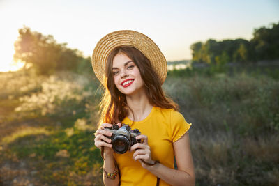 Portrait of smiling young woman holding camera