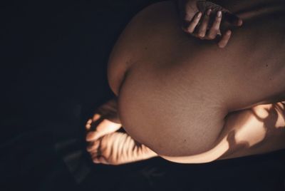 High angle view of naked woman kneeling on bed