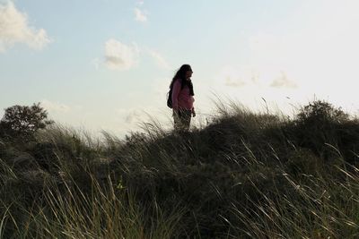 Woman standing on grassy land against sky