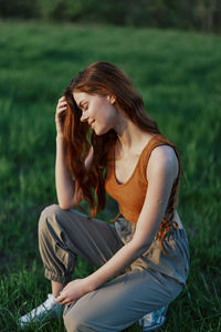 Side view of young woman sitting on field