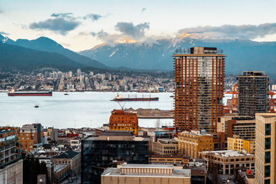 A city skyscraper view of north vancouver, gastown, mountains, water, and a soft pastel sunset