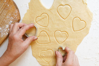 Woman hands cooking heart shape cookies on white table, valentine day 
