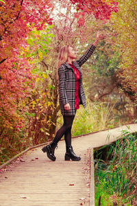 Full length of woman standing on footpath during autumn