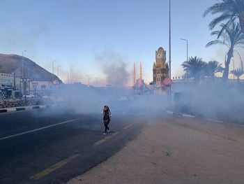 Rear view of people on street in city against sky