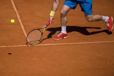 Low section of man playing tennis on court