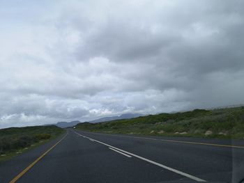 Empty road against cloudy sky