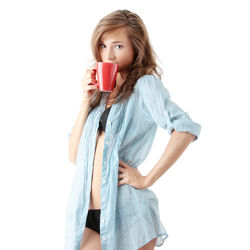 Young woman drinking coffee cup against white background