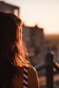 Rear view of woman standing against sky during sunset