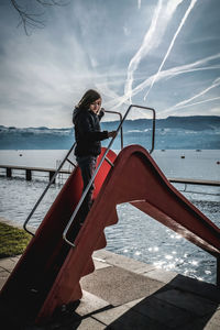 Woman standing by sea against sky