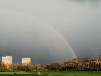 Rainbow over cityscape against sky