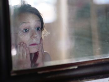 Portrait of girl looking through window