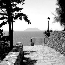 Walkway by sea against clear sky