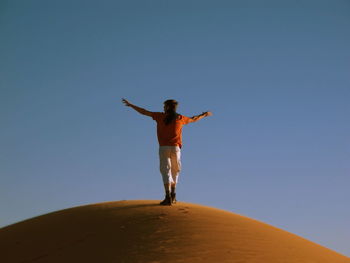 Low angle view of man standing against clear blue sky