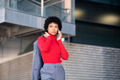 A young african-american businesswoman wearing a red turtleneck and a suit in a business building