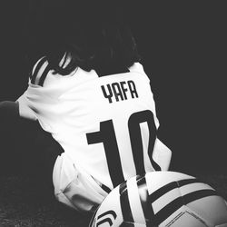 Rear view of woman sitting against black background