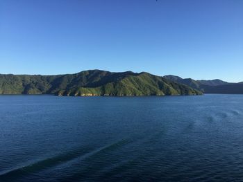 Scenic view of sea and mountains against clear blue sky