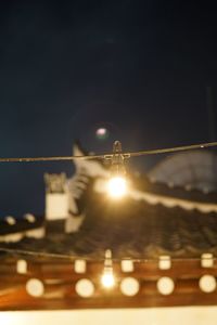 Close-up of illuminated lights against sky at night