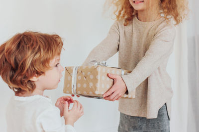 Girl giving gift box to brother at home