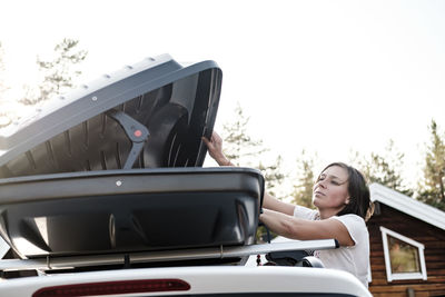 Low angle view of woman opening suitcase