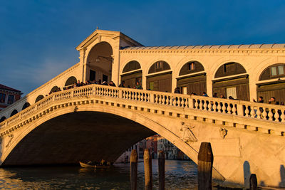 Arch bridge over buildings against sky in city