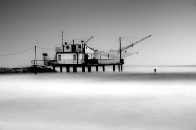 Fishing platform in sea against sky