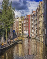 Canal by city against sky