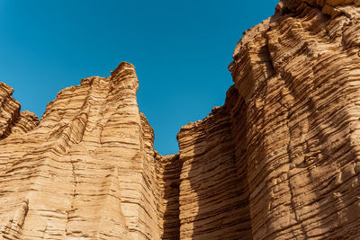 Low angle view of rock formation against clear blue sky