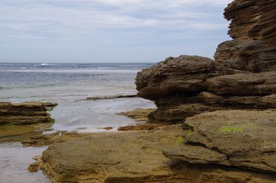 Rock formation on beach against sky