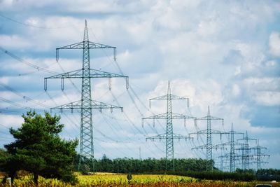 Low angle view of electricity pylon on field against sky