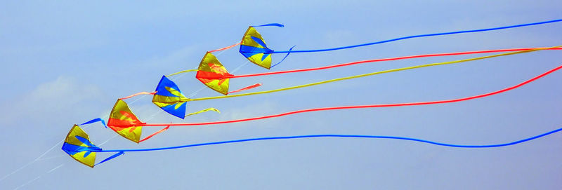 Low angle view of multi colored kite flying against blue sky