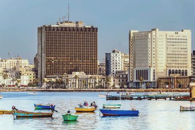 Boats moored on river with buildings in background