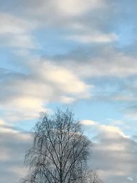 Low angle view of bare tree against cloudy sky