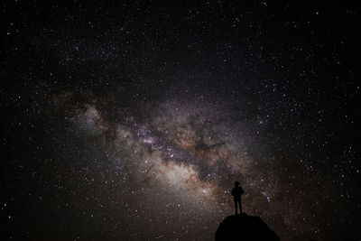 Silhouette man standing on cliff against sky at night