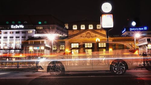 Light trails on street against illuminated buildings in city at night