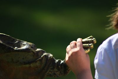 Close-up of child holding hand with a statue 