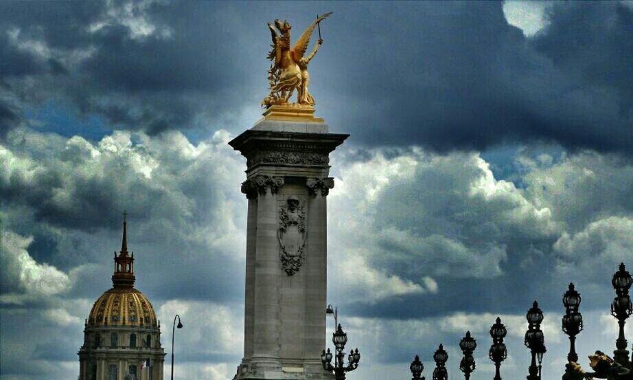 sky, low angle view, statue, cloud - sky, architecture, human representation, sculpture, art and craft, built structure, art, cloudy, creativity, history, building exterior, famous place, cloud, travel destinations, architectural column, animal representation