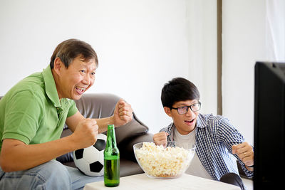 Father and son clenching fists while watching sport at home