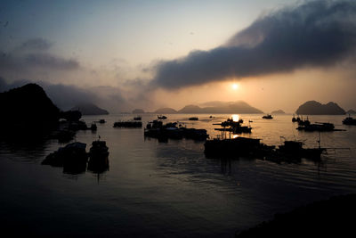 Silhouette boats in sea against sky during sunset