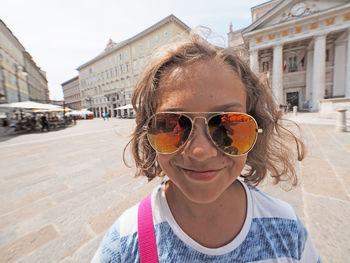 Portrait of smiling girl wearing sunglasses in city during sunny day