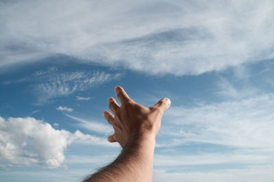 Low angle view of human hand against sky