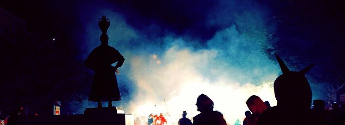 Silhouette men against illuminated sky at night