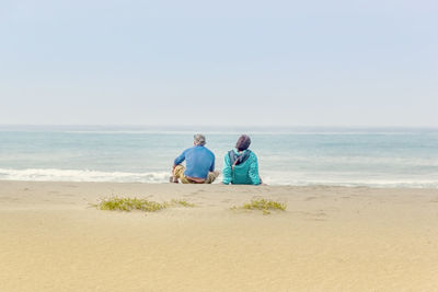 Men on beach by sea against sky