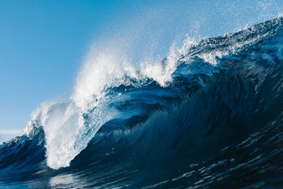 Water splashing in sea against blue sky