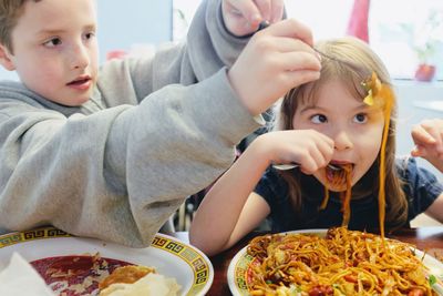 Cute siblings eating food at restaurant