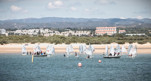 People on boats in sea against mountains