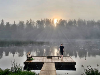 Rear view of men standing by lake against sky