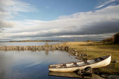 Boat moored on lake against sky