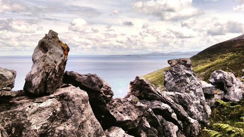 Rock formation by sea against sky